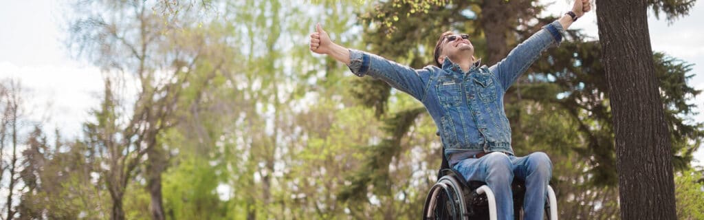 young man in wheelchair with arms raised in jubilation