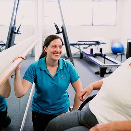 Clinic-tile Physiotherapist kneeling next to client in wheelchair in the clinic gym